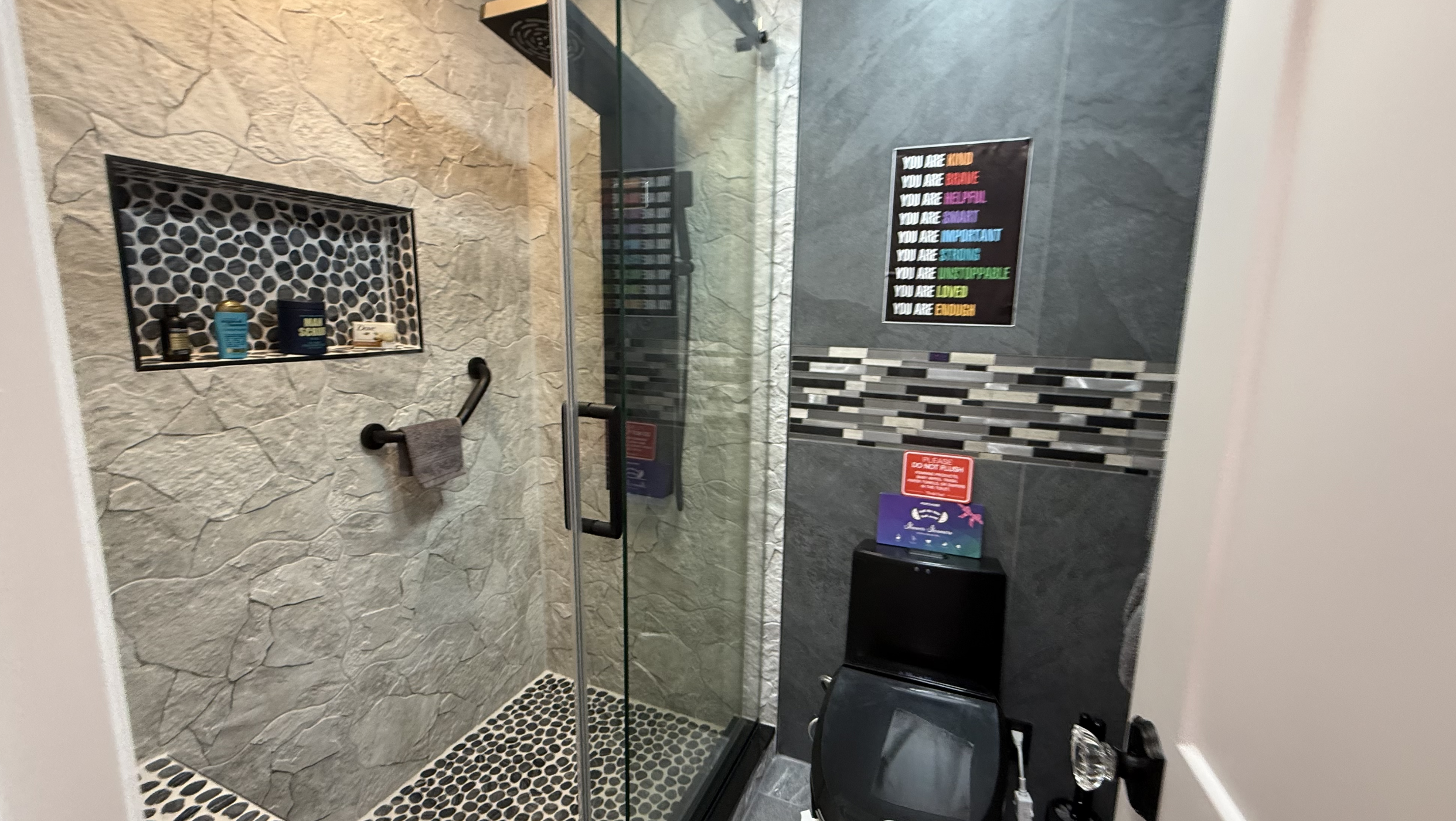 LED-lit spa shower with dark tile and affirmation posters
