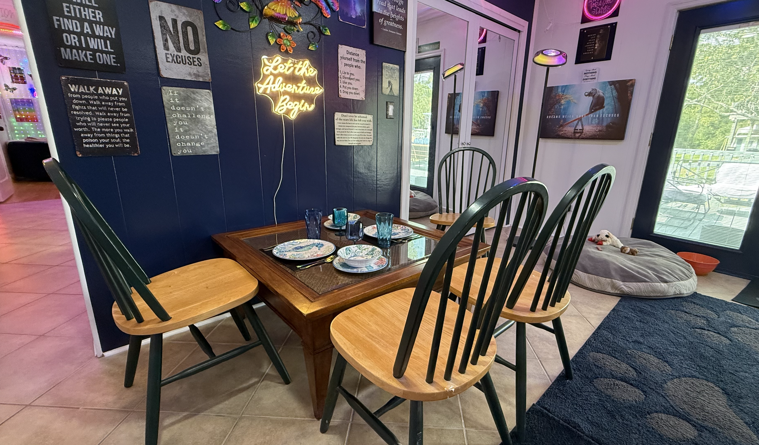 Dining area with navy affirmation wall and neon "Let the Adventure Begin"