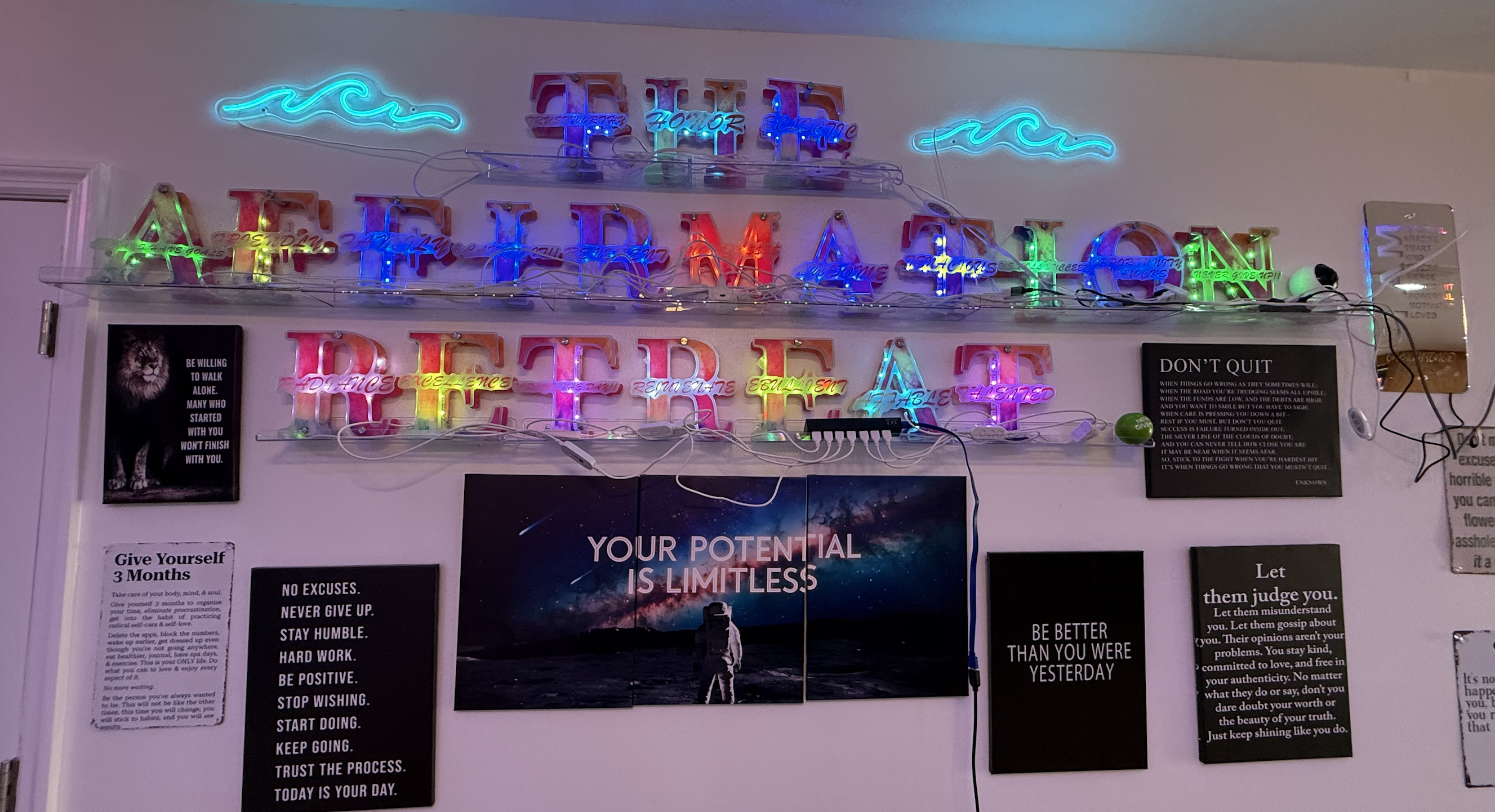 Neon "The Affirmation Retreat" wall with motivational posters